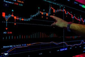 Main pointant des graphiques boursiers analysés avec des métriques financières sur un écran.
