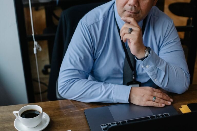 Homme d'affaires réfléchissant devant son ordinateur portable dans un bureau.