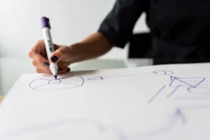 Main dessinant avec un marqueur sur du papier, capturant une planification créative.