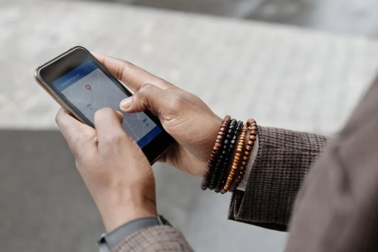 Mains avec bracelets naviguant sur smartphone avec une application GPS en extérieur.