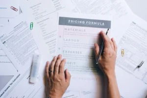 Mains organisant des documents commerciaux et des papiers de formule de prix sur un bureau.