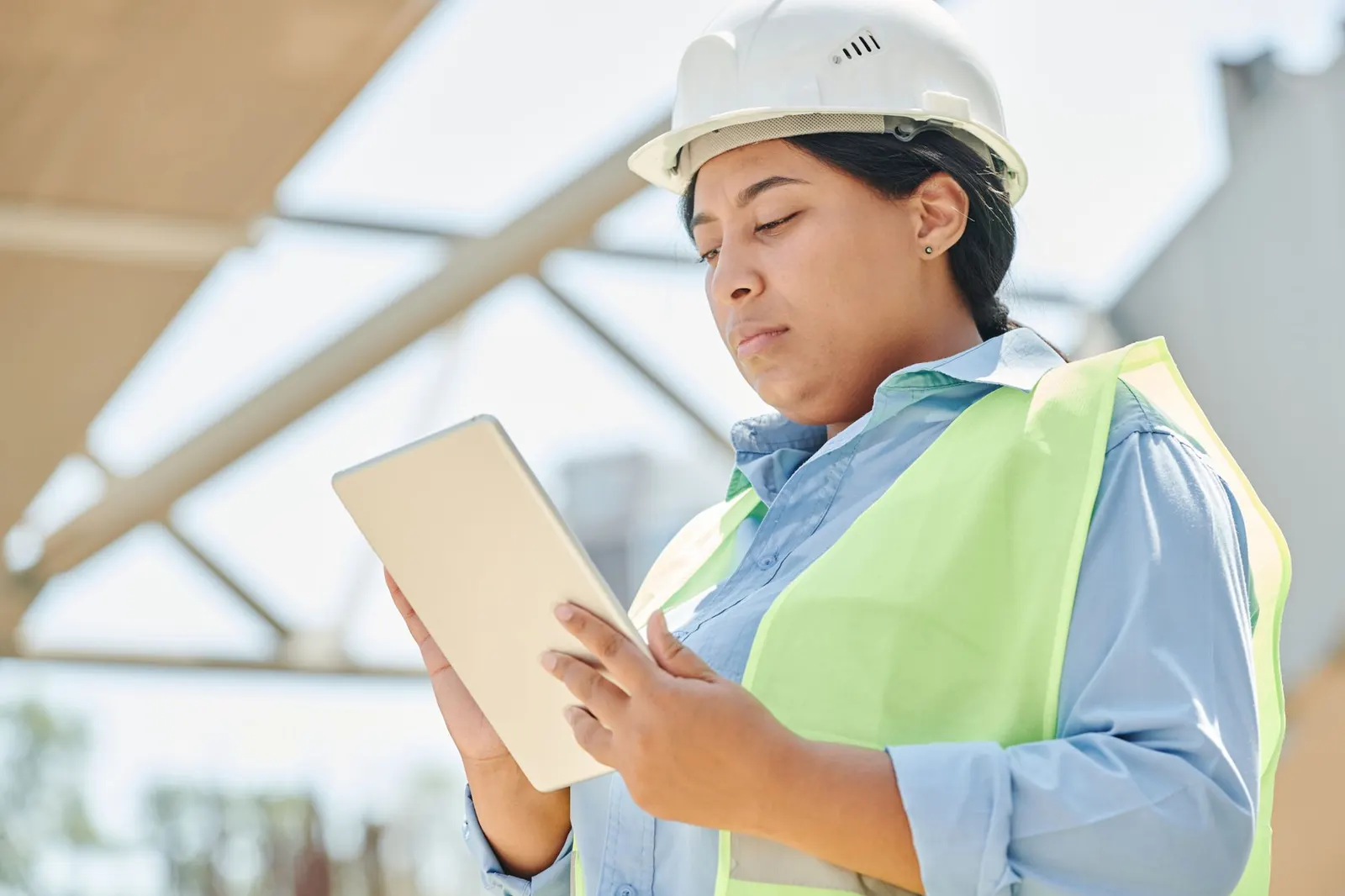 Ouvrier du BTP utilisant une tablette sur un chantier, avec une carte géolocalisée à l'écran.